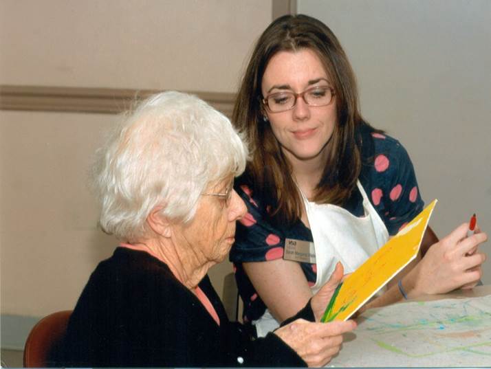 An Alzheimer's patient observing a painting with their caregiver